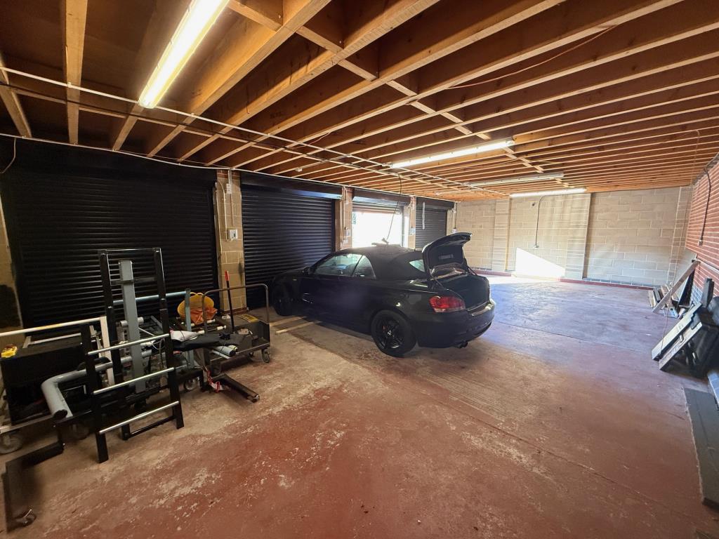 Lot: 78 - GARAGES AND FORECOURT WITH POTENTIAL - Open plan garages inside showing the depth and height